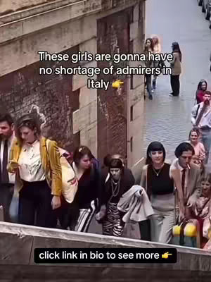 A group of people are walking down a stone staircase, the shot is taken from a high angle looking down. The women are dressed in a variety of outfits. Overlay text appears across the image, as well as the words 'click link in bio to see more' in a black box on the bottom.