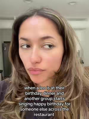 A woman with long, wavy light brown hair is positioned in front of a neutral background that includes a glimpse of an interior space behind. She looks slightly off-camera, seemingly reacting to something. The text overlay is in white, with the black background at the bottom.
