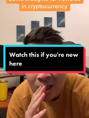 A selfie-style video cover image. In the foreground, a man is shown with his hand covering his mouth, a gesture of surprise or secrecy. He has short, dark hair and is wearing a yellow shirt. Behind him, partially visible, are some muted abstract paintings on a wall. A text overlay reading 'Watch this if you're new here' is placed across the center of the image.