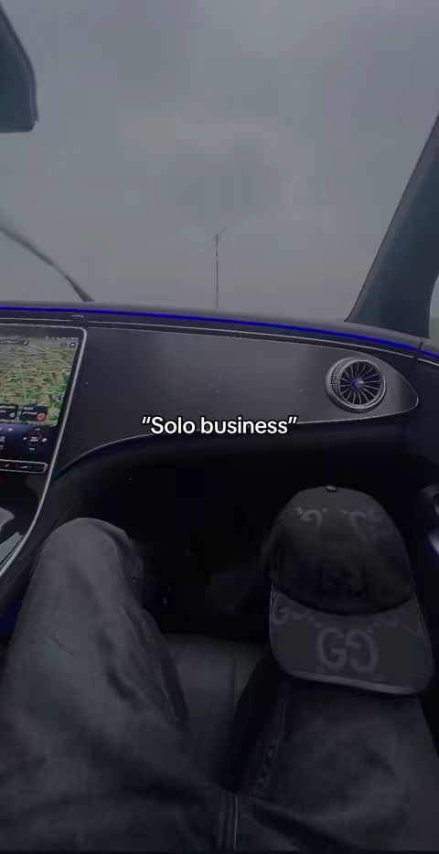 The image captures the interior of a car, seen from the driver's perspective. The dashboard is dark, with a navigation screen visible. The car's windshield wipers are in use, suggesting rain or wet conditions, and the view outside is overcast. "Solo business" is written in white text in the center of the image.