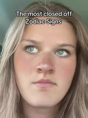 A close-up shot features a fair-skinned woman with blonde hair, looking slightly upwards and to the left. The text overlay reads “The most closed off Zodiac Signs”. The lighting appears soft, and the overall composition focuses on the woman’s face against a blurred background.