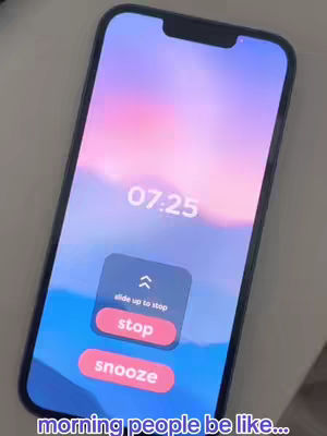 A close-up shot of a smartphone displaying an alarm clock interface. The screen shows the time as 07:25, with large digital numbers. Below the time, a dark blue box features a prompt to "slide up to stop" with an upward arrow, and two red buttons labeled "stop" and "snooze." The screen's background has a gradient of purple, pink, and blue, suggesting a sunrise or sunset. The caption is at the bottom of the image.