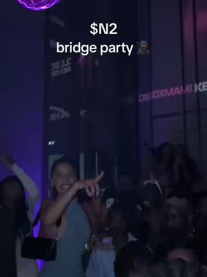 A woman in a blue dress points her finger in the foreground with a background of a party atmosphere with a purple light shining at the top.