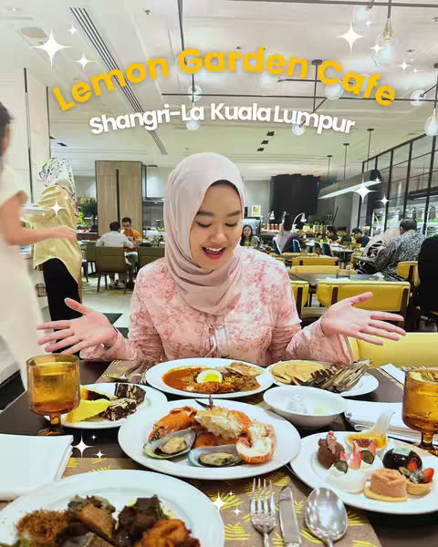 The cover image shows a woman smiling and holding out her hands, looking at the camera, standing in a restaurant. In front of her is a table filled with plates of food including seafood, desserts, and drinks. The text overlay includes the name of the restaurant, Lemon Garden Cafe, and Shangri-La Kuala Lumpur.
