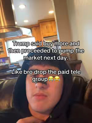 A selfie-style video image featuring a young man in a hoodie against a blurred interior background. Text overlays are present, addressing financial advice and the crypto market. The man is looking directly at the camera. The background shows a kitchen area.