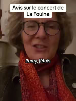 A woman with glasses and silver hair is in close-up, with text overlays. She is wearing a black jacket and a red scarf. The background is blurred.