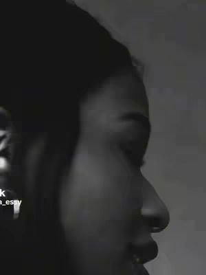 A close-up, black and white shot of a person's face in profile, emphasizing the eye and profile features. The face is turned to the right, with the person's hair obscuring part of their face. The lighting and contrast are high to give the image a dramatic feel.  The image is slightly noisy, which gives it a gritty aesthetic.