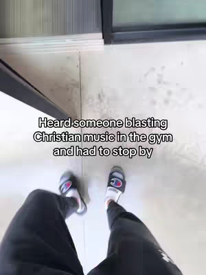 A first-person perspective shot from above, showing a person's legs and feet in sandals and a black sweatpants, standing on a light-colored floor. Text overlayed.