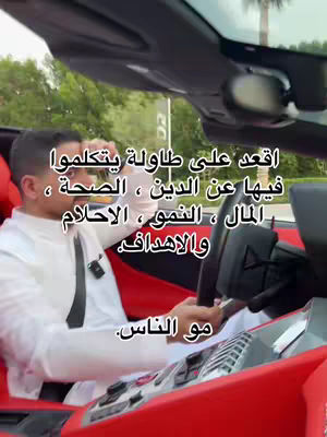 A man in a white shirt and black tie is sitting in the driver's seat of a red convertible. The image is taken from a low angle, looking up toward the car's interior. The background is blurred, showing trees and a glimpse of the sky. Text overlays the image in white.