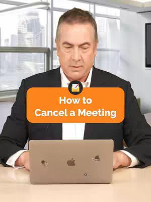 The cover image shows a middle-aged man in a suit sitting at a desk with a laptop. An orange rectangle with white text that reads 'How to Cancel a Meeting' is over the image. Behind him is a large window showing a blurred city view.
