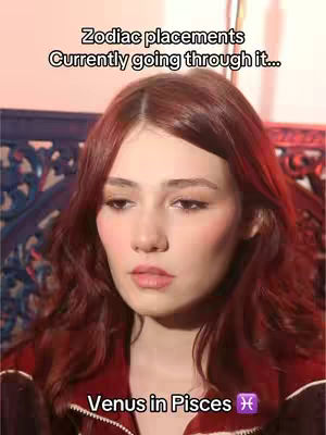 The cover image features a medium shot of a woman with auburn hair. She is looking slightly off-camera with a neutral expression. The background is blurred and appears to be a textured wall. Text overlays at the top reads \"Zodiac placements Currently going through it...\" and at the bottom \"Venus in Pisces\" followed by the Pisces zodiac symbol.