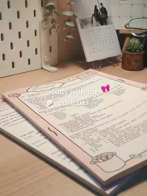 The cover image shows a study desk with a stack of open notebooks and some items like calendar and plant. The foreground features open paper pads with pink borders. The background contains a white pegboard, a part of calendar, and a small plant set up. The overall tone is bright and organized, ideal for study content.
