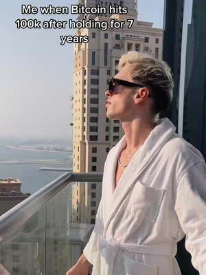 A man in a white robe and sunglasses is standing on a balcony, looking out at a city and ocean view. The background features a tall building, and text is overlaid on the image.