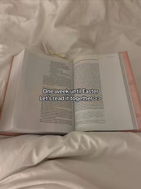 An open book lies on a white bed sheet. The book is open, displaying text on both pages. Overlaid on the image is text.
