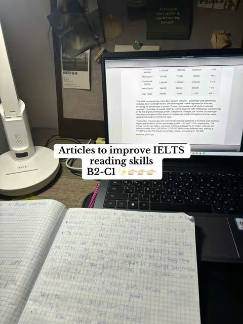 A desk setup with a laptop displaying a document, an open notebook with handwritten notes, and a desk lamp. A whiteboard and other objects are in the background adding depth to the composition.
