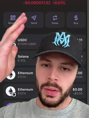 A man wearing a black baseball cap interacts with a phone interface displaying financial data, possibly crypto market trading.