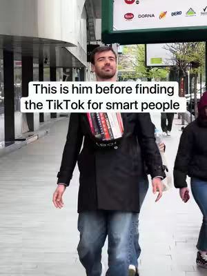 A man wearing a black coat and jeans walks toward the camera on a city sidewalk. Text is overlaid on the image.