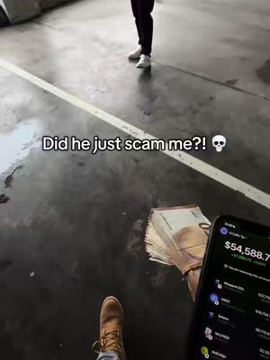 A first-person perspective shot in an outdoor, urban setting. The primary visible elements include the creator's lower body wearing brown boots, stacks of money held in their hand, and a smartphone displaying a financial app. The background features the legs and feet of another person, the ground and a directional line. Overlay text appears on the image.