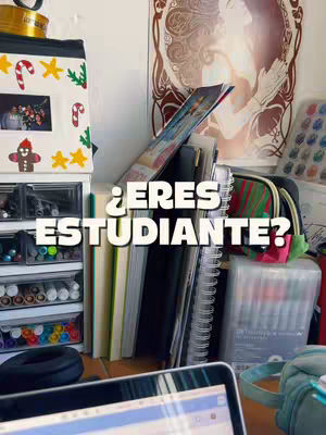 A cluttered desk with books, stationery, and other items with the text overlayed in white on top of the image: '¿ERES ESTUDIANTE?'