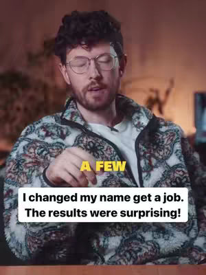 A man with glasses and a patterned jacket is the central focus. Text overlays are present, the background is blurred with warm lighting.