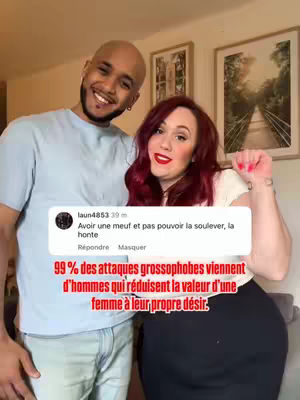 A selfie-style shot of a couple. The woman is holding her fist up, looking at the camera. Overlay text includes a post and a comment about the value of a woman. The background is blurred, with hints of a room's interior apparent.
