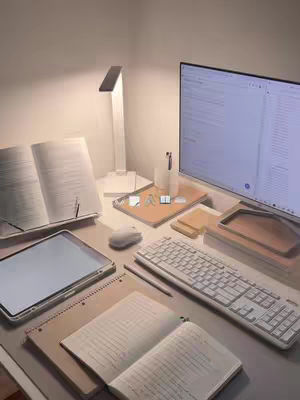 The cover image presents a well-lit desk setup with a variety of items arranged on a light-colored surface. A large monitor displays a screen, alongside an open book, a tablet, a keyboard, notebooks, pens, and desk accessories. The lighting appears soft and even, and with the books and the stationary, suggesting the user is studying.