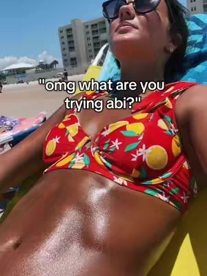A selfie taken on a sunny beach of a person lying down, wearing sunglasses and a red flowered bikini, with the hook text overlayed on top.