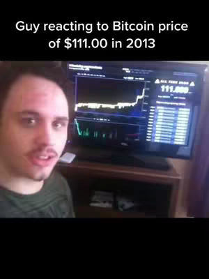 A man is on the left side of the screen looking towards the camera, he is wearing a green shirt and has short brown hair. Behind him, a large screen displays a Bitcoin price chart with the price listed as $111.00 in 2013.