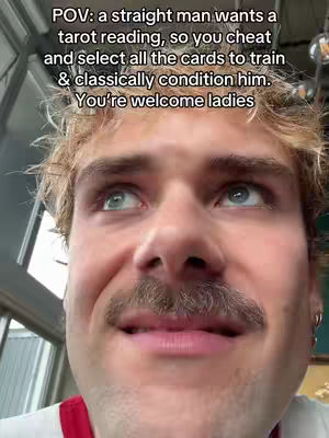 Close-up shot of a man with short, light brown hair and a mustache, looking upwards with a slightly amused or sly expression. Overlay text in white describes a humorous scenario involving a tarot reading.