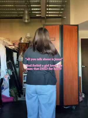A person is standing in a well-lit room, facing away from the camera. They are wearing a black shirt and light blue pants. Text overlay is added to the image.