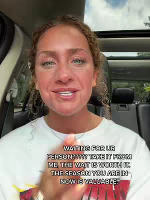A woman with curly blonde hair is inside a car, looking directly at the camera and speaking. She is wearing a white t-shirt. Text overlays appear near the bottom of the frame promoting a message of patience and worth in waiting.