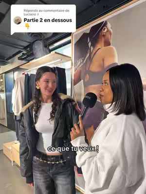 The cover image shows two young women in a store setting. One woman holds a microphone and speaks towards the camera. The other woman smiles and faces the camera. Behind them is a large poster with a woman in workout gear and a clothing rack. The scene is well-lit, and the composition is balanced, emphasizing the interaction between the two women.