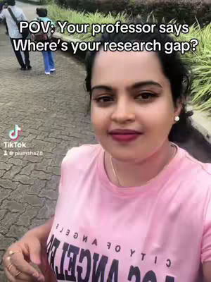 A selfie-style video featuring a woman in a pink top, standing outdoors with a pathway and greenery in the background. Text overlayed on the image asks 'Where's your research gap?'