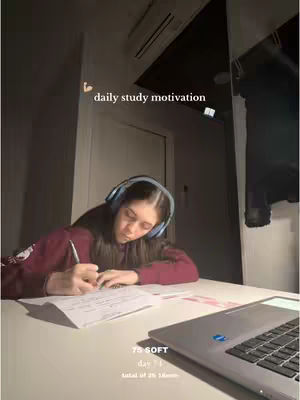 The cover image shows a lit room with a person seated at a table, studying. She is wearing a maroon top and headphones. The table has a laptop and papers. The text 'daily study motivation' is added at the top right.