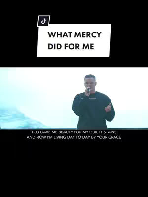 The cover image displays a man holding a microphone on a stage, likely during a performance, with text overlays against a black background. A white rectangle has text overlay reading "WHAT MERCY DID FOR ME" in bold, sans-serif font. Below, there is a line lyrics "YOU GAVE ME BEAUTY FOR MY GUILTY STAINS, AND NOW I'M LIVING DAY TO DAY BY YOUR GRACE".