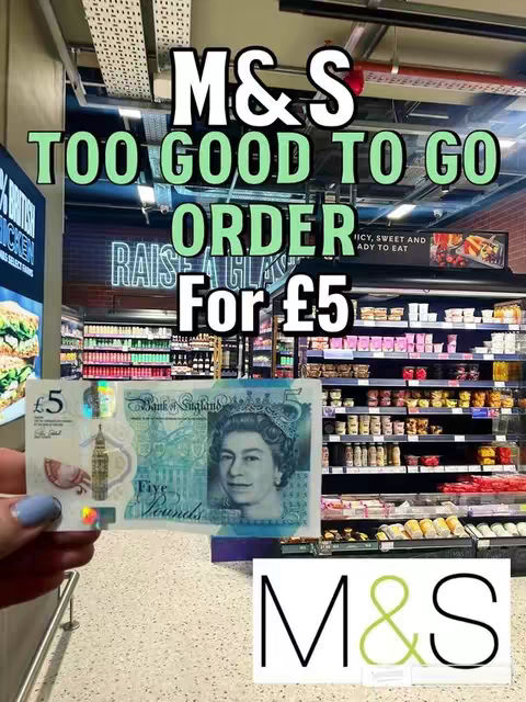 A person holds a British £5 note in their hand in front of shelves of food items in a Marks & Spencer (M&S) store. The store's logo and the text "M&S Too Good To Go Order For £5" are prominently featured. The image is brightly lit, showcasing the store's interior and the food offerings.