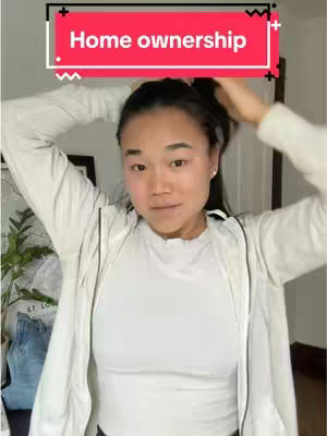 A woman with dark hair is shown from the mid-chest up, standing, and pulling her hair back. She is wearing a white top and a white jacket. A text overlay in a red box that reads 'Home ownership' is positioned above her head.