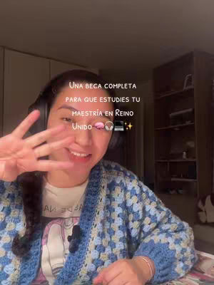 A woman wearing headphones and a blue and white patterned cardigan smiles at the camera, holding up her hand with fingers spread. Text overlay indicates the video's content.