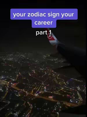 An aerial view at night, possibly from a plane window, showing a city's lights below. The sky is dark, the city lights are yellow and white with a purple text overlay near the top of the image.