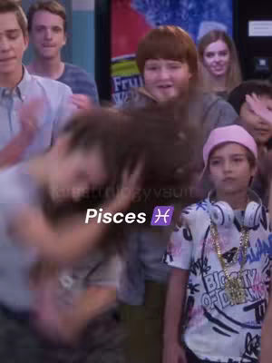 A group of young people are in a room, with some appearing to be dancing or moving. The focus is on a young person in the foreground wearing a backwards baseball cap who is looking towards the right. The background shows other people, some looking towards the action and others looking towards the camera.