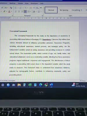 The image shows a laptop screen displaying a Word document. The document contains text outlining a conceptual framework for a study related to child sexual abuse awareness in a specific barangay. The laptop's keyboard is visible at the bottom, and the screen's interface shows various Word processing tools.