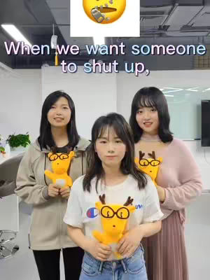 Three young women stand close together in front of an office-like setting. The middle woman is holding a yellow deer plush toy, while the other two hold a deer too, with the text overlayed at the top saying,"When  we want someone to shut up."