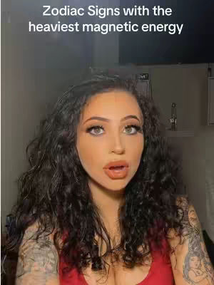 A woman with long, dark curly hair and tattoos on her arms gazes directly at the camera with a surprised expression. The background is neutral, and the focus is centered on the woman's face, framed with a hook text overlay.