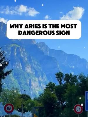 The cover image is dominated by a scenic mountain landscape under a bright, cloud-filled blue sky. In the foreground, green trees and road signs provide context. The text overlay, "WHY ARIES IS THE MOST DANGEROUS SIGN", is placed in a white rounded rectangle.