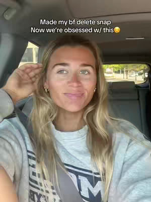 A woman with blonde hair smiles while seated in a car. The background includes the car interior and a view of an outdoor scene. Text overlays are present and the video emphasizes on a relationship theme.