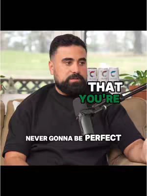 The cover image features a man with a beard wearing a black shirt, seated indoors with a microphone in front of him. Text overlays state 'THAT YOU'RE' and 'NEVER GONNA BE PERFECT'. The background includes a window, drinks, and some greenery.