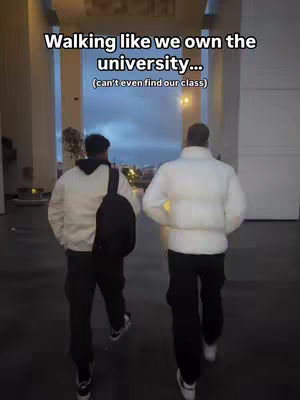 Two young men walk away from the camera, framed by an archway. The background shows a cloudy sky and city lights. Text overlayed reads "Walking like we own the university... (can't even find our class)".