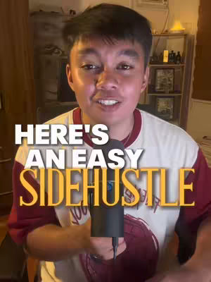 A man stands in front of a room. The man is holding a microphone and wearing a t-shirt with writing on it.  The image has text overlays.