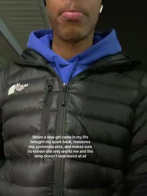 A selfie-style shot featuring a young man from the chest up, wearing a dark jacket over a blue hoodie. His lips are slightly pursed, and he appears to be in an indoor setting. Text is overlaid on the image.
