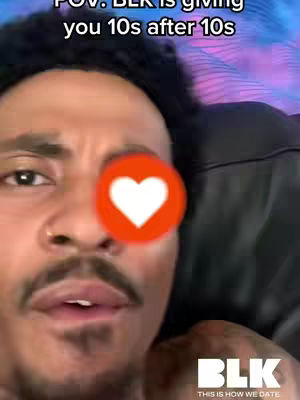A close-up of a dark-skinned man with short curly hair and a groomed mustache and goatee. He is looking straight at the camera with a slightly open mouth. Overlayed on the image is a red heart with a white filled-in heart. Above him is text, and the BLK app logo is at the bottom.